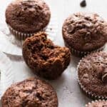 6 Chocolate chip muffins with one having a bite missing.