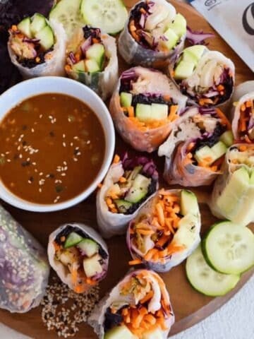 A wood plate of kimchi summer rolls with dipping sauce