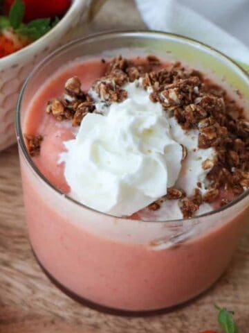 A strawberry smoothie with cream on top.