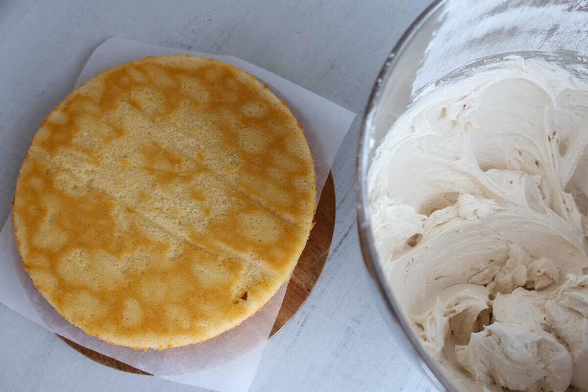 A vanilla cake and bowl of frosting.