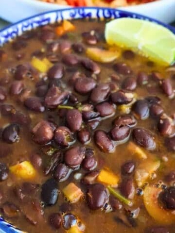 Vegan black beans with a lime wedge in a blue bowl.