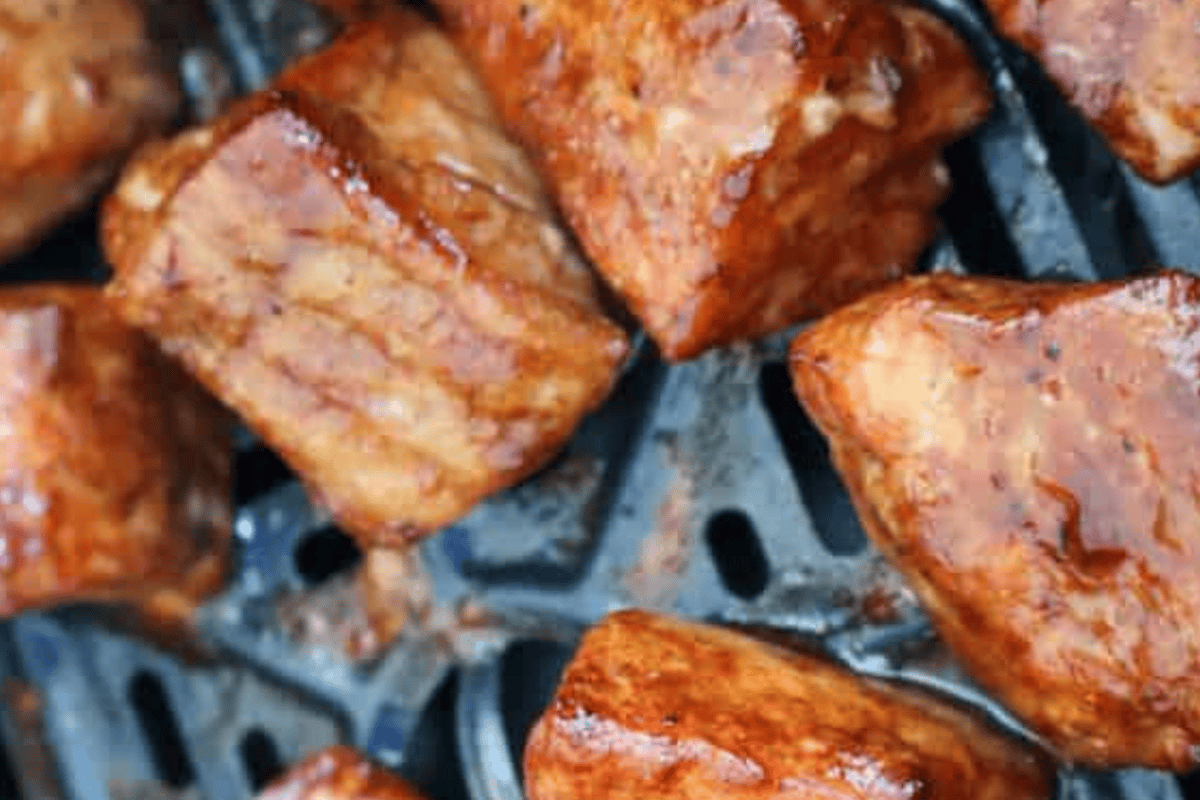 Salmon air fryer bites cooking in an air fryer tray.