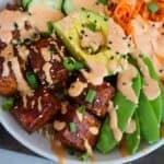 A bowl of air fryer salmon bites on with veggies, avocado and rice.