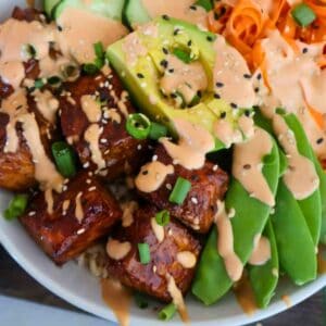 A bowl of air fryer salmon bites on with veggies, avocado and rice.