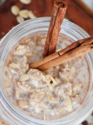 Cinnamon Roll Overnight Oats with cinnamon sticks coming out the top.