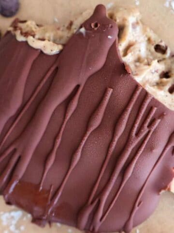 A frozen peanut butter yogurt bar on a baking sheet with chocolate chips.