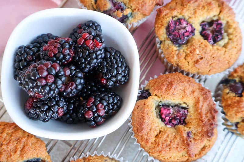 Close up of muffins with a white cup of rasberries on the side