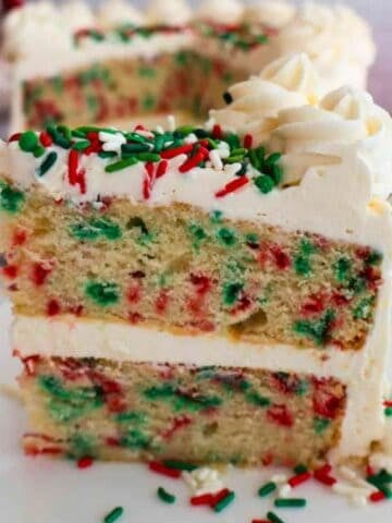 A slice of Gluten-Free Almond Vanilla Cake with a larger cake in the background.