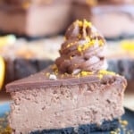 Slice of chocolate orange cheesecake topped with dollop of chocolate frosting.