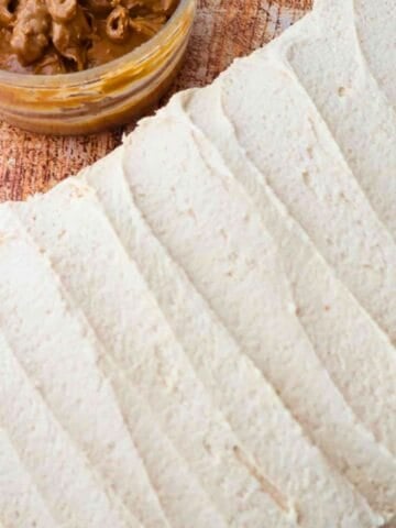 An overhead shot of peanut butter cream cheese frosting next to a jar of peanut butter.