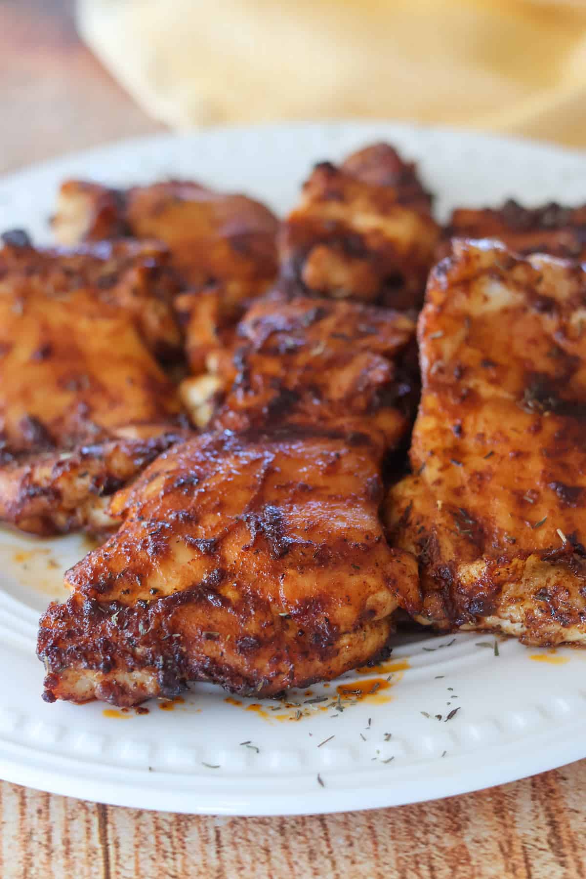 Six cooked boneless skinless chicken thighs on a white plate.