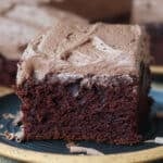 A slice frosted chocolate banana cake on a plate.
