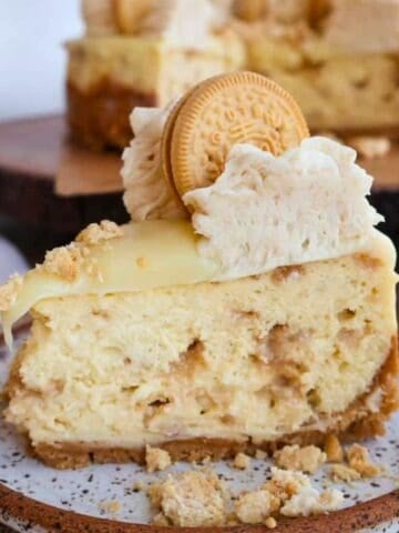 Golden Oreo cheesecake slice topped with whipped cream and an Oreo cookie.