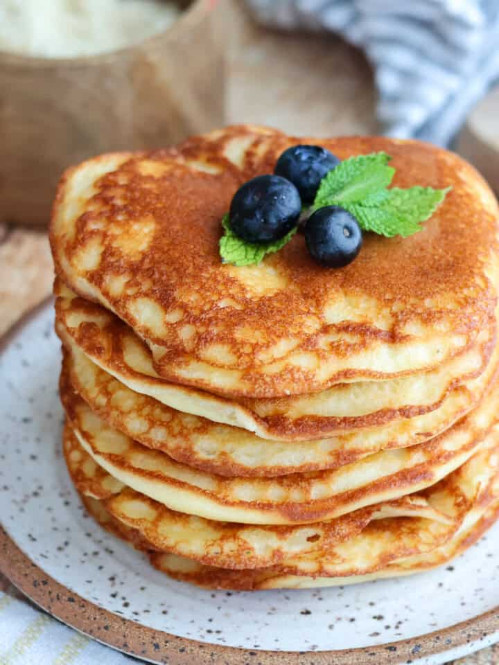 Stack of pancakes topped with blueberries.