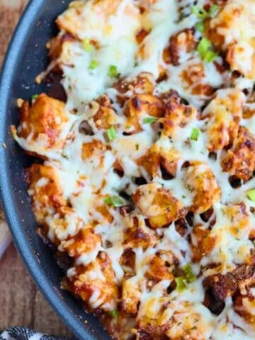 Cheesy BBQ chicken and potatoes in skillet.