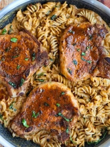 Overhead shot of skillet full of pasta and pork chops.
