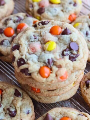 A stack of Reese's Pieces Peanut Butter Cookies on a cooling rack.