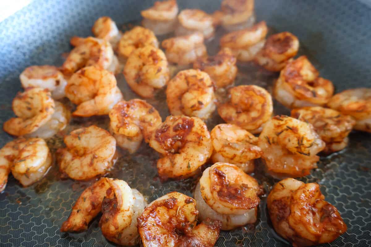 Skillet with cooked, seasoned shrimp. 