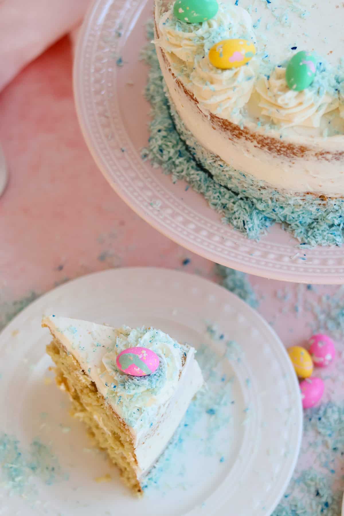 Slice of coconut cake next to plate with whole coconut cake.