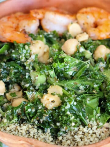 Bowlful of kale salad with hemp seeds and shrimp.