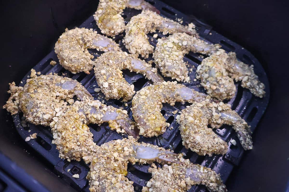 An air fryer basket with breaded shrimp.