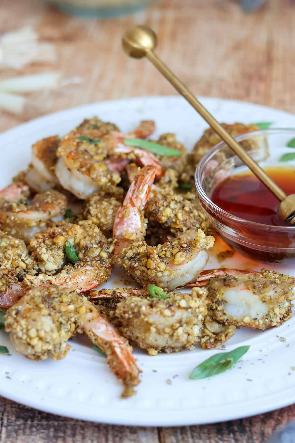 Plateful of breaded air fried shrimp with bowl of hot honey.