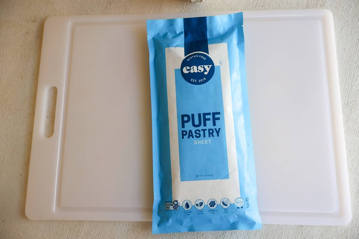 A package of puff pastry sheets on a white cutting board.