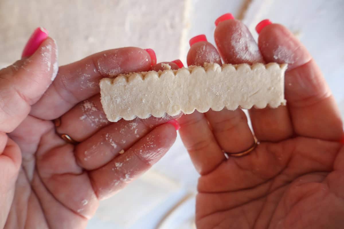 Hand holding a puff pastry strip. 
