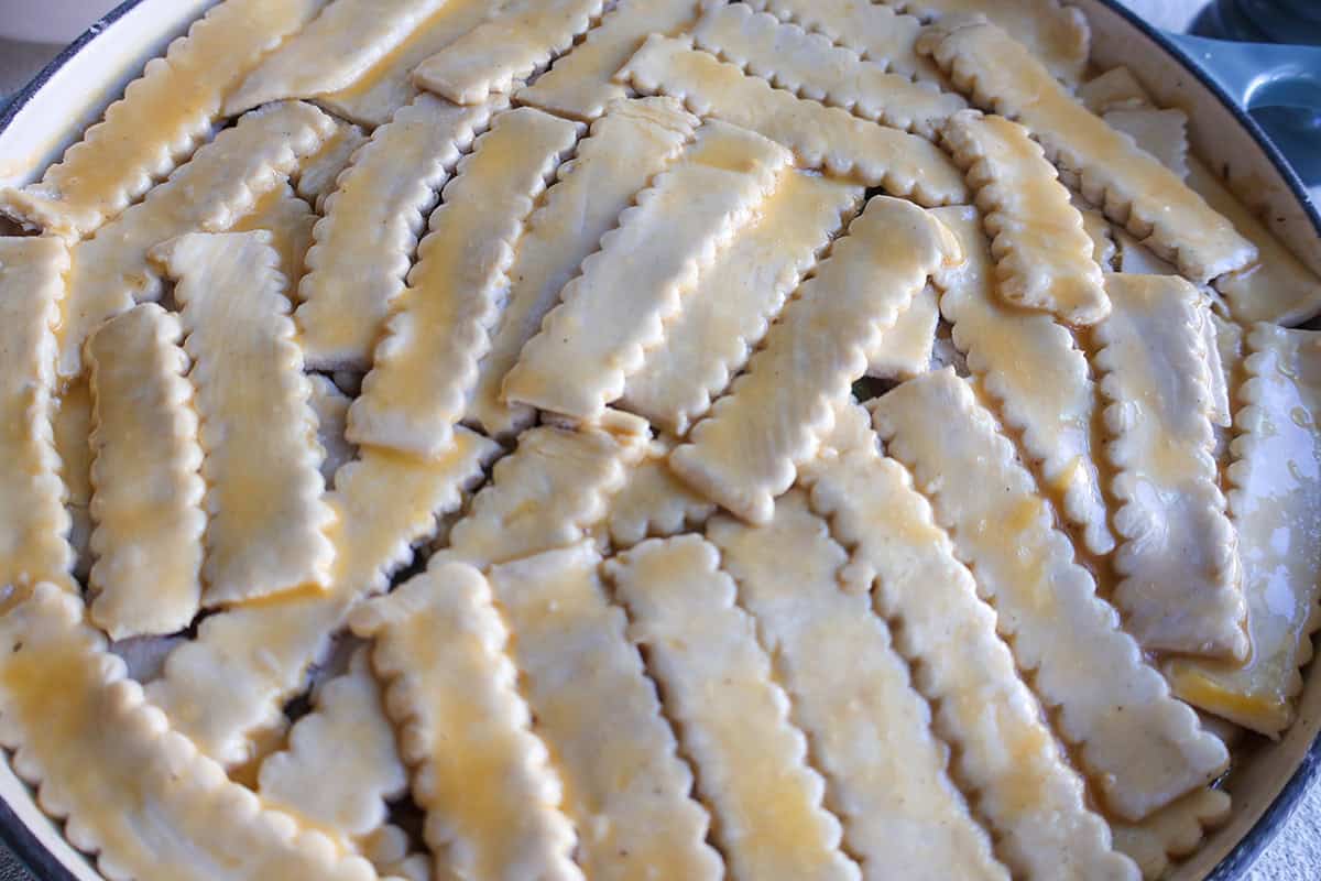A skillet full of pot pie with unbaked puff pastry on top. 
