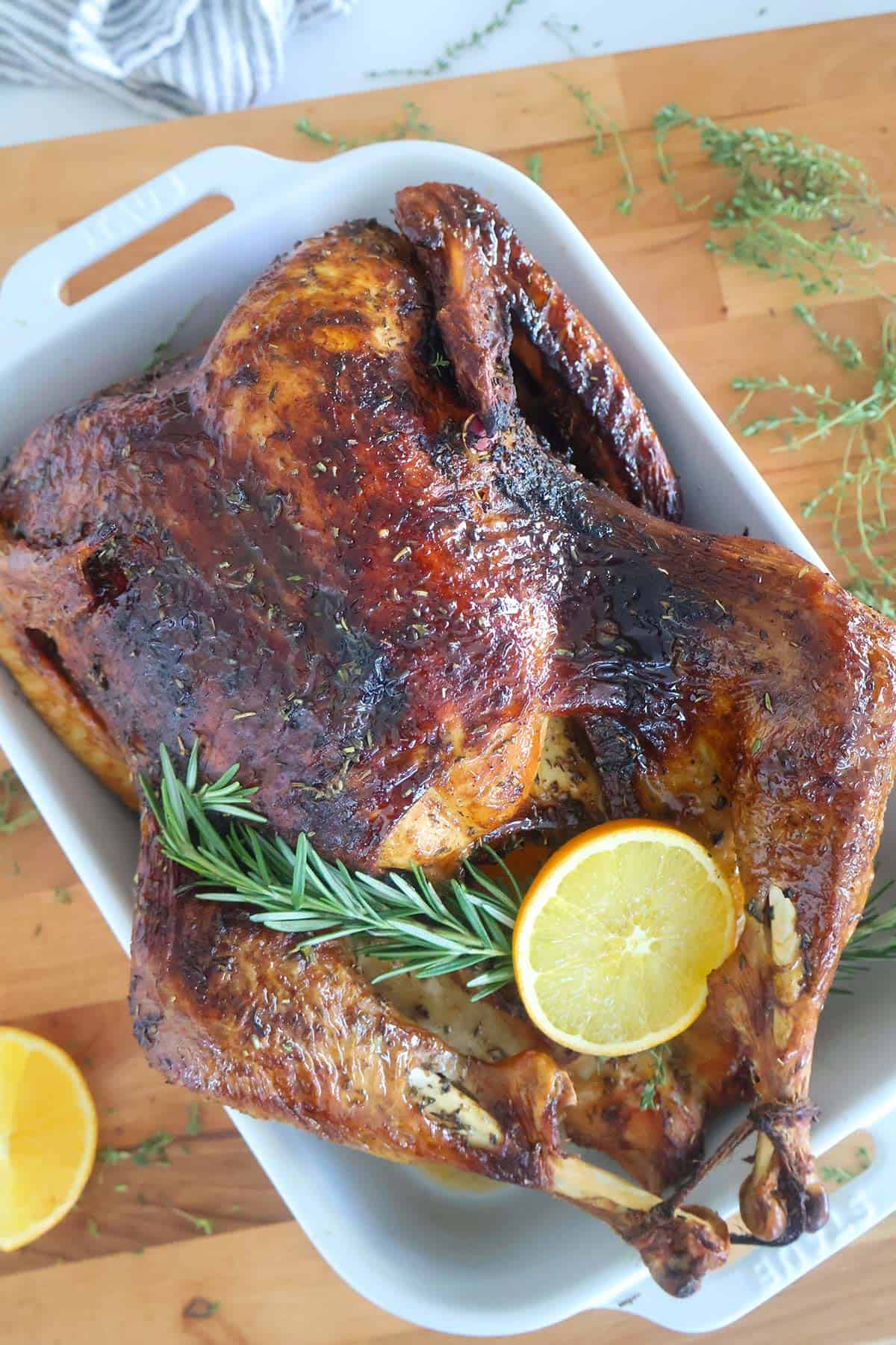 A whole roasted turkey in a white baking dish. 