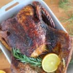 A white baking dish with a roasted turkey.