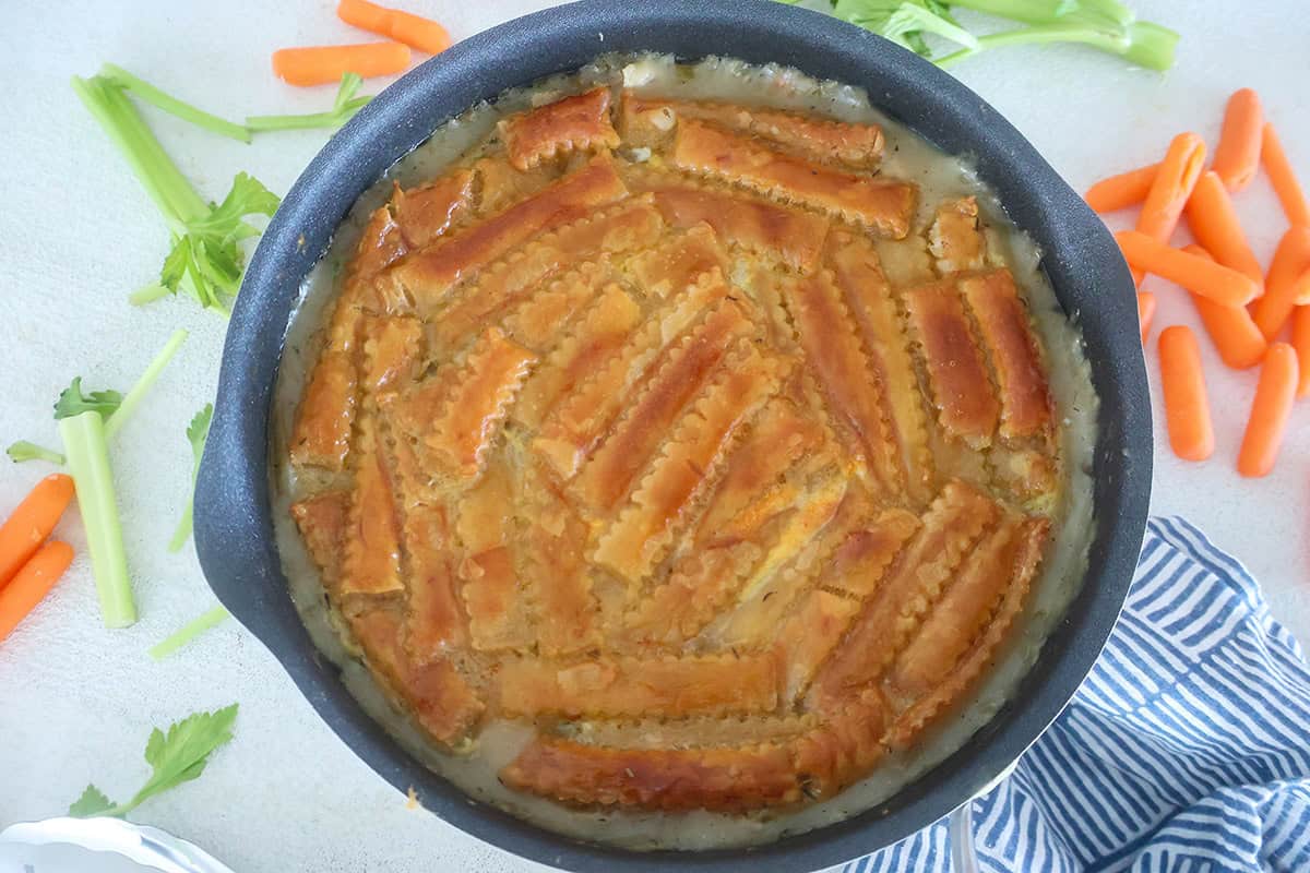 A skillet full of baked pot pie with a golden puff pastry crust.