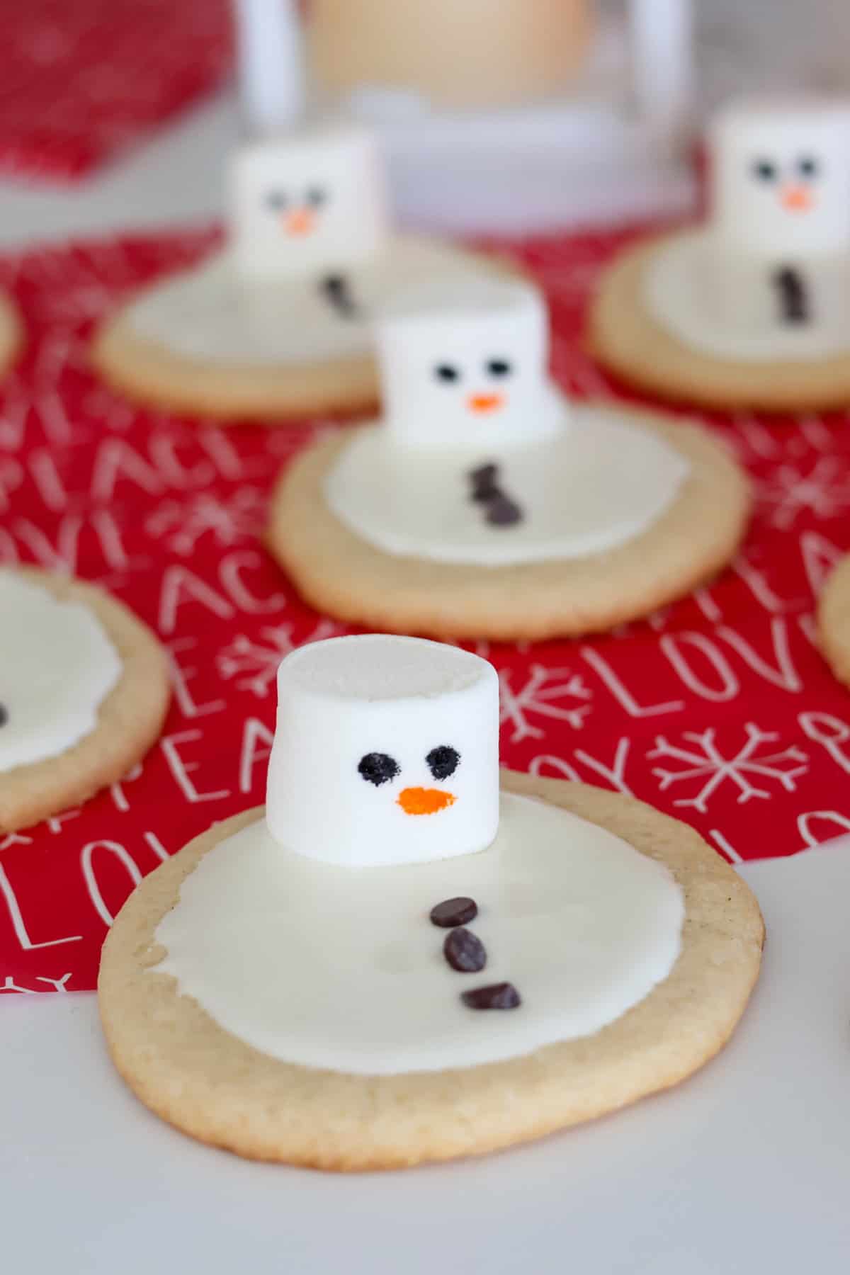 Melted Snowman Cookies on red holiday paper.