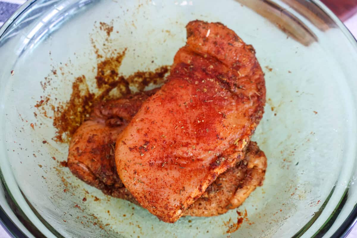 Chicken seasoned in a glass bowl.