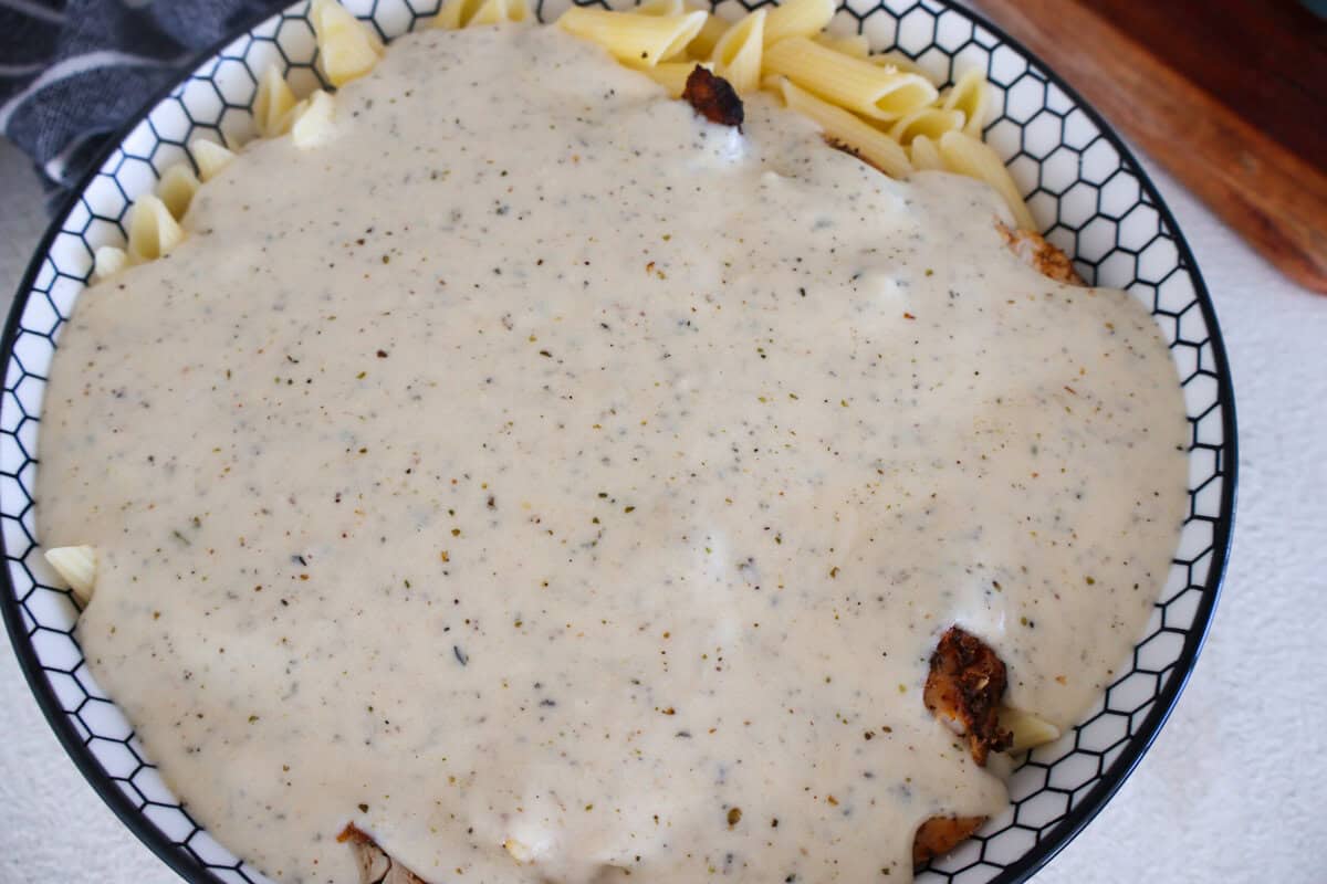 Pasta and diced chicken covered in a creamy cheese sauce in a bowl.