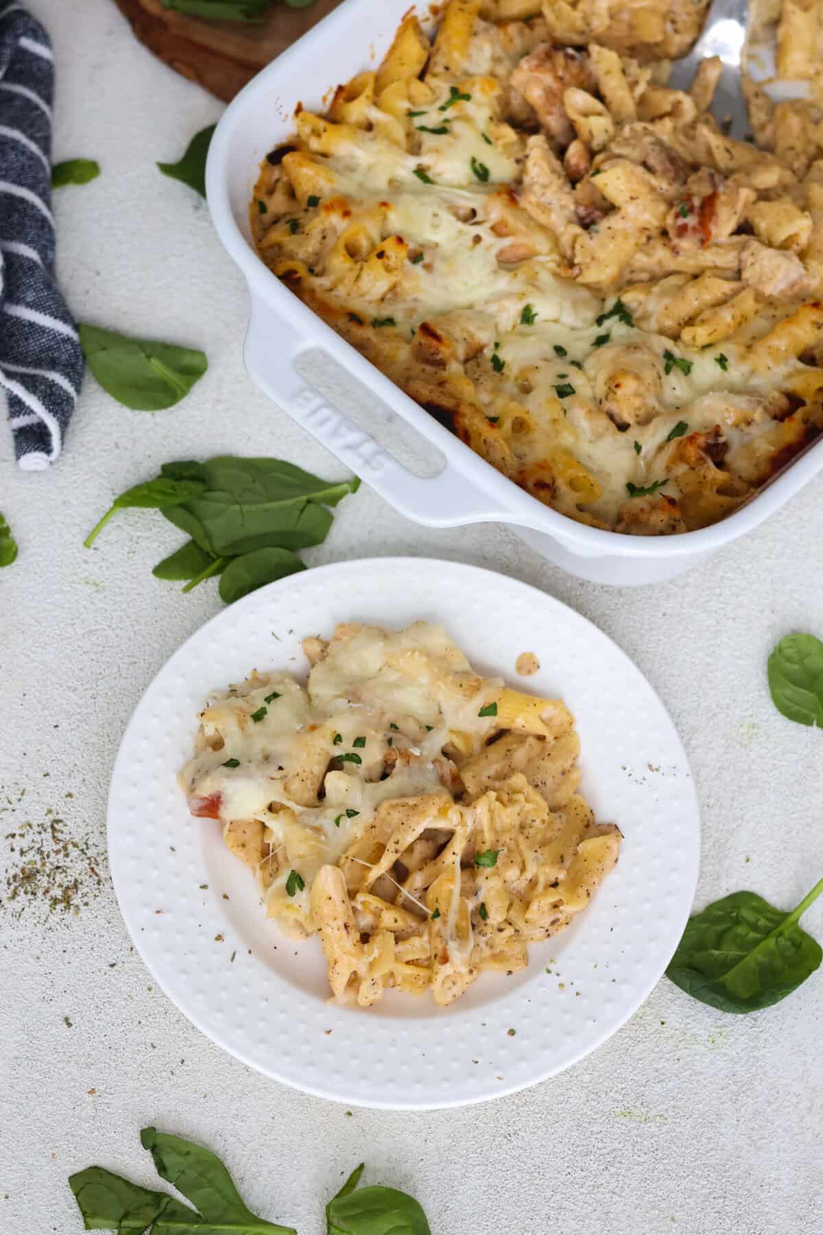 A plate of Chicken and Pasta Alfredo bake next to a dish of more Alfredo bake.