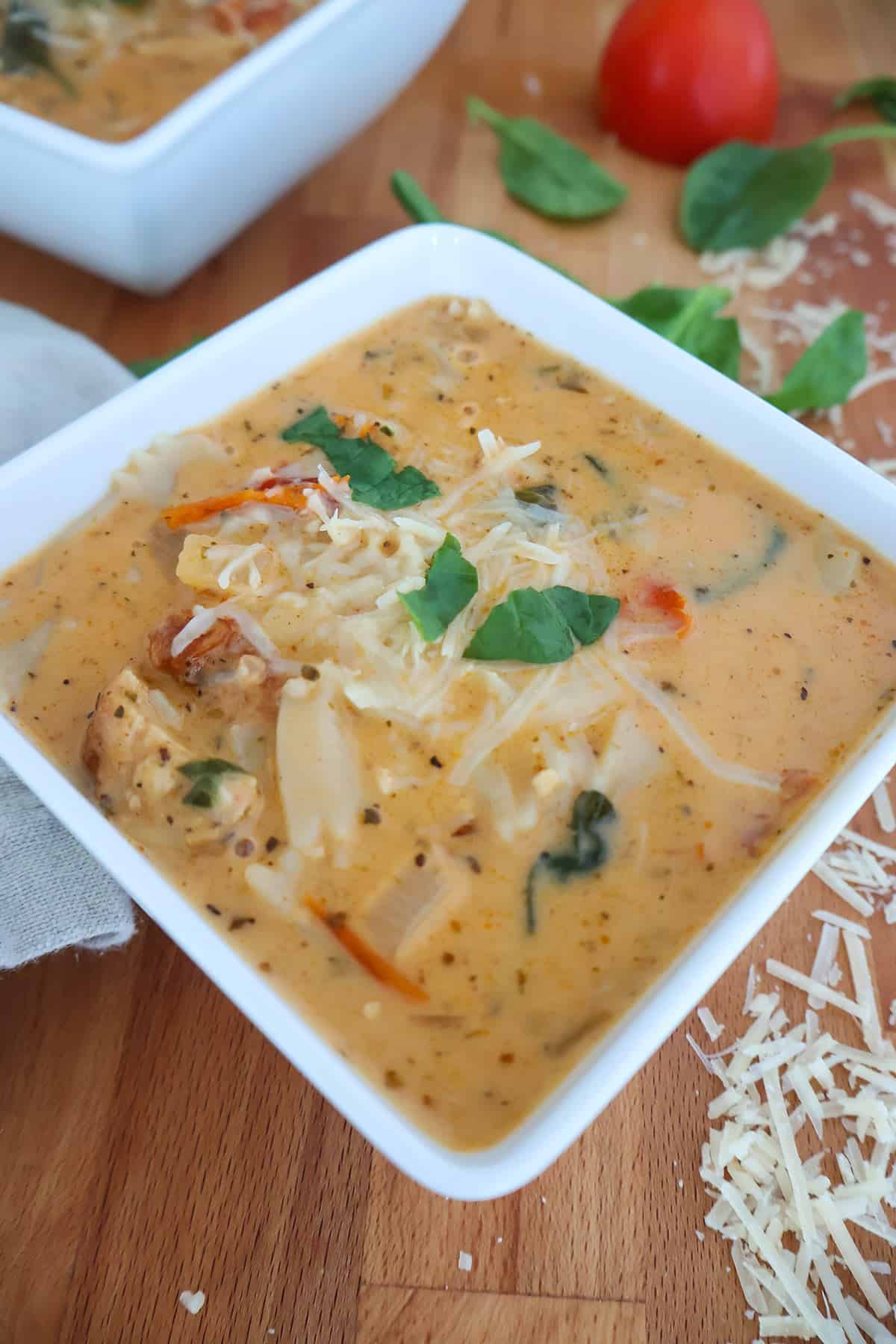 A white, square bowl filled with creamy chicken soup. 