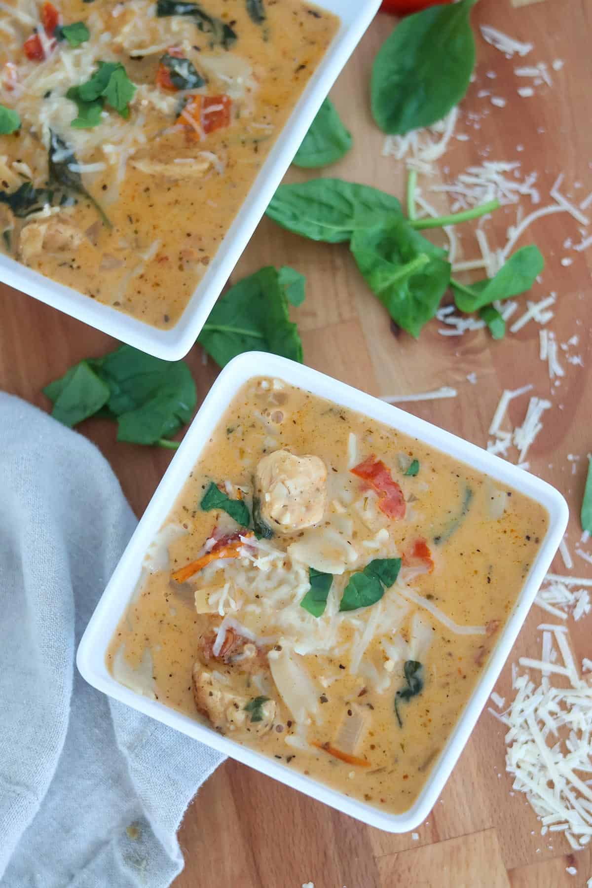 Two white, square bowls full of creamy chicken soup.