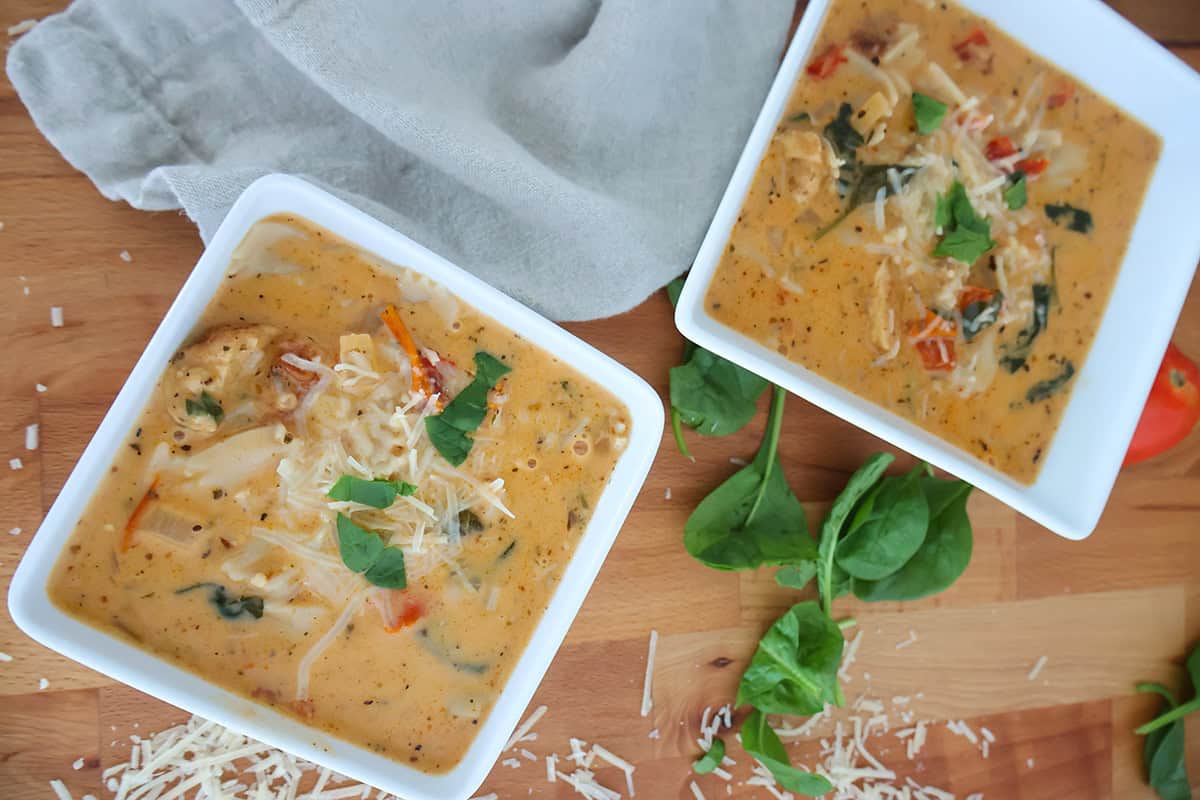 Two white, square bowls filled with creamy chicken soup.