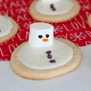 A Melted Snowman Cookie on red holiday paper.