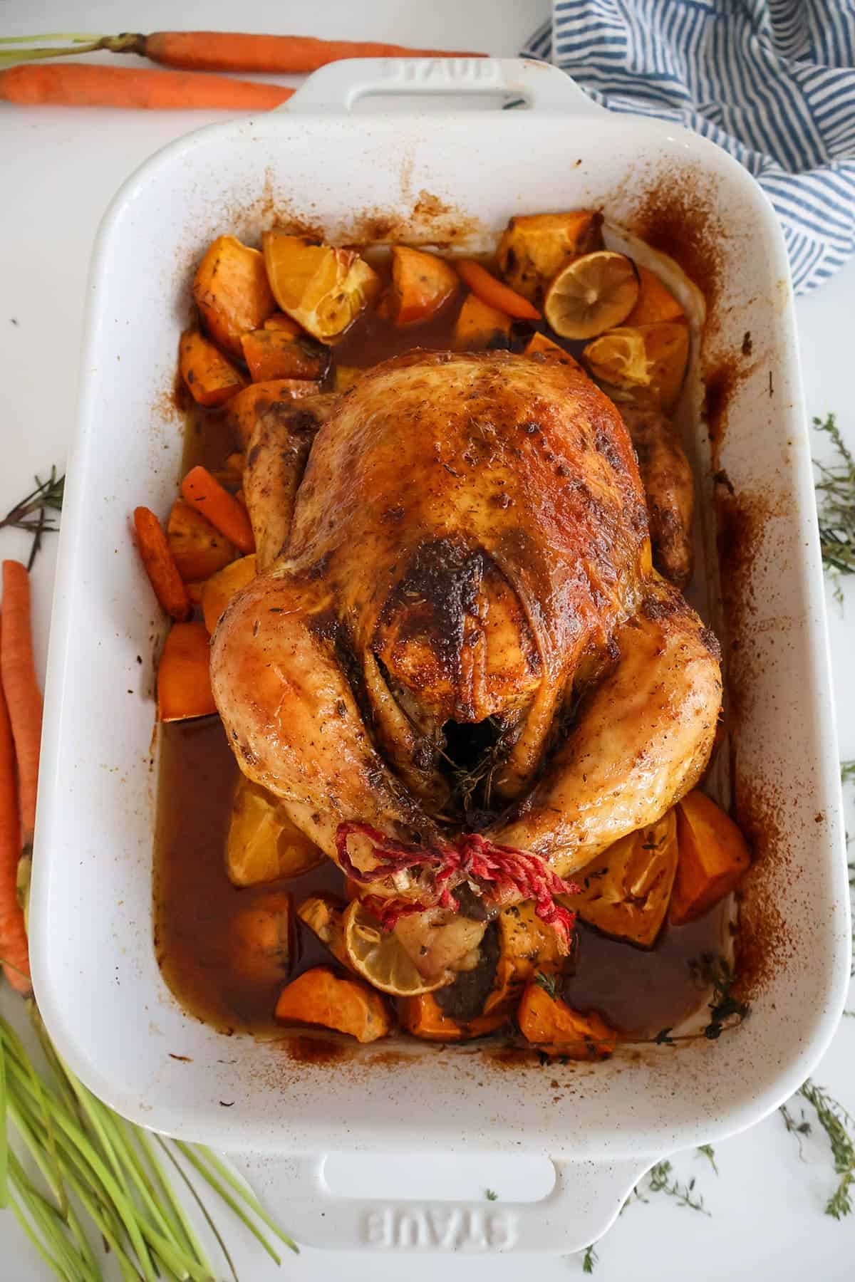 A whole baked chicken in a white baking dish.