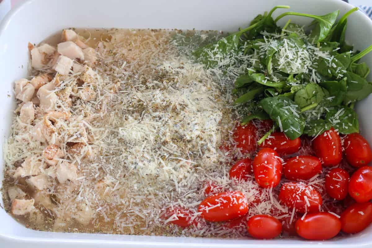 Ingredients for a dish of Spinach and Artichoke Orzo Pasta bake with cheese on top.