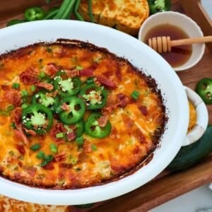A casserole dish of Jalapeño Popper Dip on a wooden tray