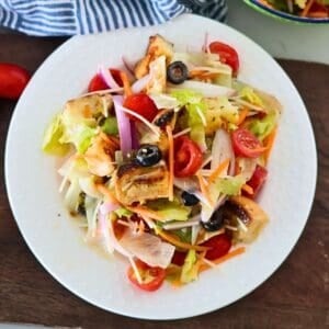 A white plate of Olive Garden Copycat House Salad on a cutting board.