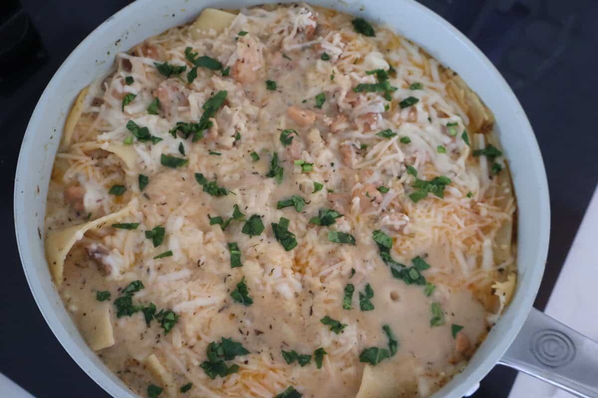 Gluten Free Chicken Alfredo in a pan covered in cheese and garnished.