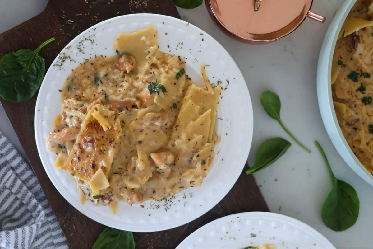 Gluten Free Chicken Alfredo garnished on a white plate on a black cutting board.