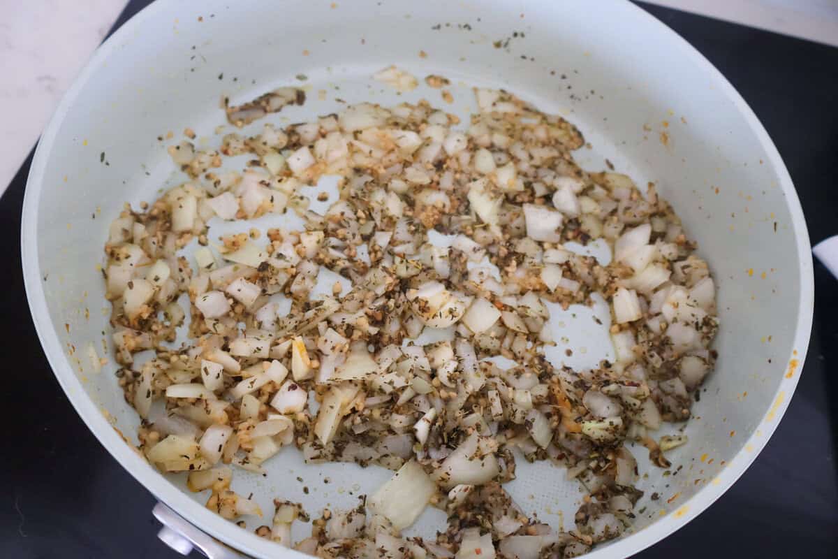 A skillet of onion and seasonings cooking together.
