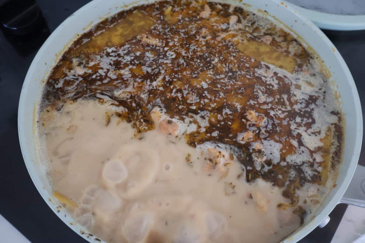 A skillet of milk and chicken stock cooking together.