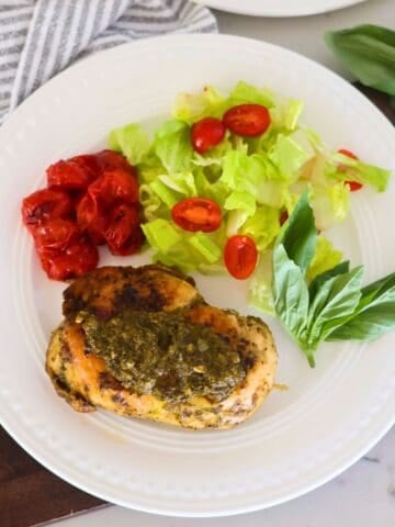A plate of Grilled Chicken Pesto and a side salad and tomatoes