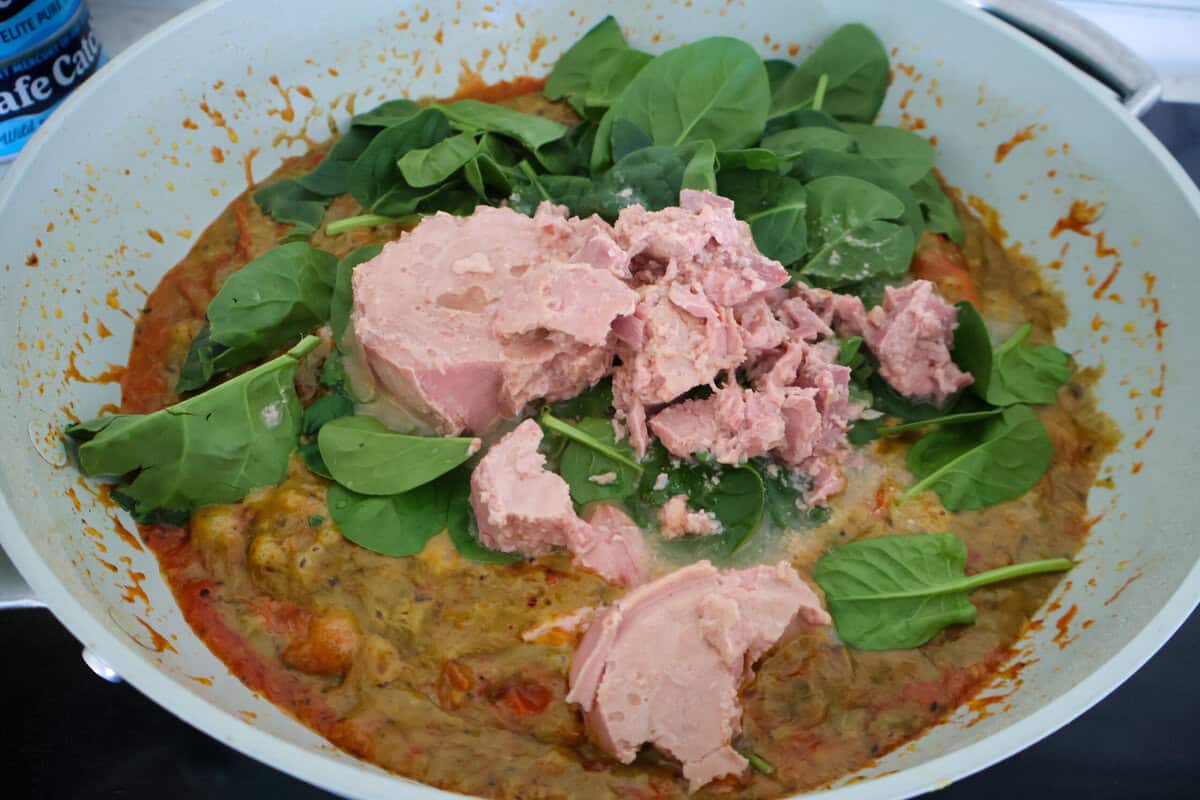 Canned tuna and spinach in a pan with pesto sauce.